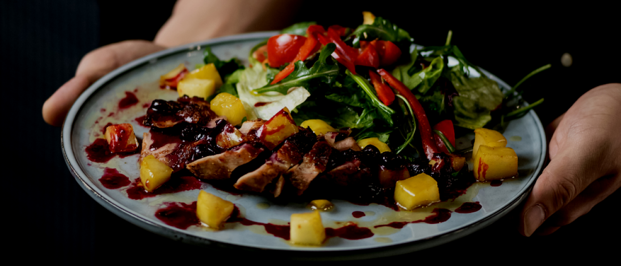 Ensalada de solomillo de cerdo a la plancha con mango, aguacate y salsa de arándanos. 